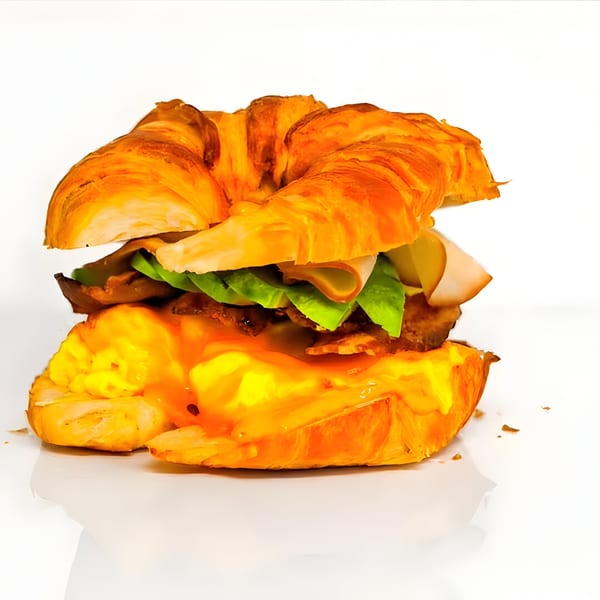 A croissant sandwich filled with turkey, lettuce, and a generous amount of melted cheese.